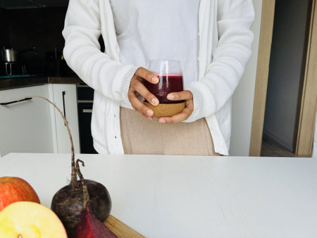 Woman holding a glass of fresh juice in the kitchen at home. Beetroot juice. Healthy lifestyle conceptの写真素材