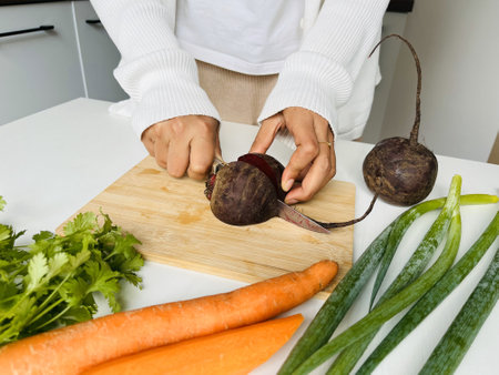 Closeup of a woman's hands cutting beetroot on a wooden chopping board. Healthy Vegetables. Healthy eating and dieting concept.の写真素材