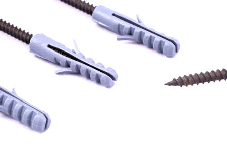 Three screws with dowels in a row on a white background, with another screw without a dowelの写真素材