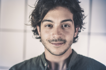 An handsome young man, 20Y, is posing in studio in a surprise pose looking at the camera. White skirt. Retroilluminated booths in the background.の写真素材