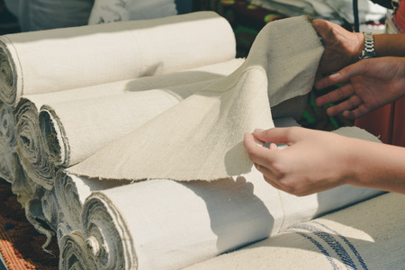 Female hands are touching rolls of linen cloth a the market, valuating the purchase.の写真素材