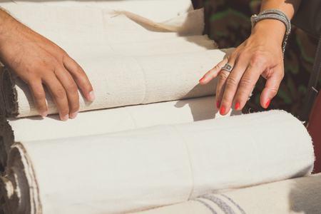 Female hands are touching rolls of linen cloth a the market, valuating the purchase.の写真素材