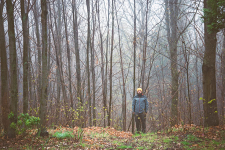 Man standing in a foggy forest and looking at the camera.の写真素材