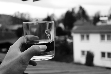 A glass of whiskey in hand and view on countrysideの写真素材
