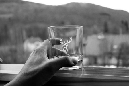 A hand holding a glass of whiskey and the view of the countrysideの写真素材