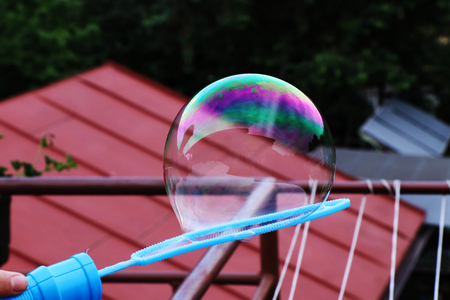 A colourful bubble attaching on bubble blower use as decoration. On the top of bubble is green and...