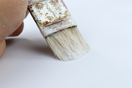 A some man painting wall using white colour. A old small brush for accuracy. White backgroundの写真素材