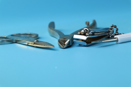 A view on manicure things as scissors, nail file, special scissors on nails. Blue background