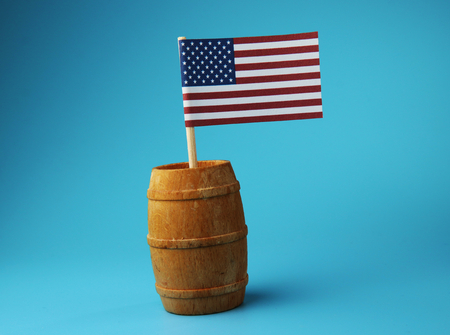 A national flag of USA on wooden stick in wooden barrel on blue background. A small paper flagの写真素材