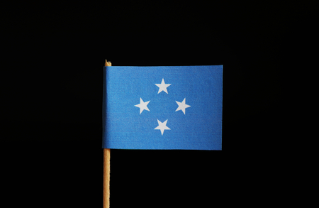 A national flag of Federated States of Micronesia on wooden stick on black background. The federation belongs to Oceania. Group of islands.の写真素材