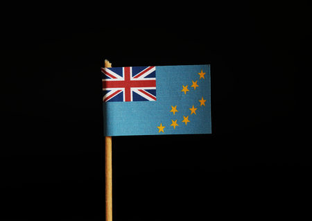 A Flag of Tuvalu on wooden stick on black background. Flag has same symbol as great britain. Tuvalu belongs to Oceania.の写真素材