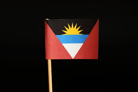 A official Flag of Antigua and Barbuda on wooden stick on black background. State located in central america and it is island country. There lived mainly africanの写真素材
