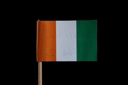 A official flag of Ivory Coast on toothpick and on black background. The Ivory Coast is located in west africa. Flag is tricolour of orange, white and green.の写真素材