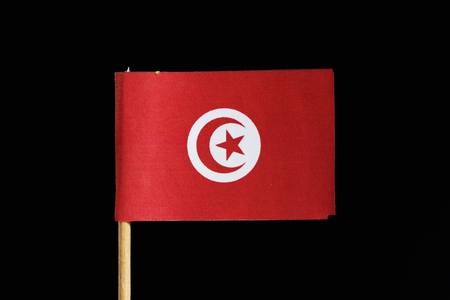 A official and original flag of Tunisia on toothpick on black background. Consists from red field with a centered white sun-disc containing a red star.の写真素材