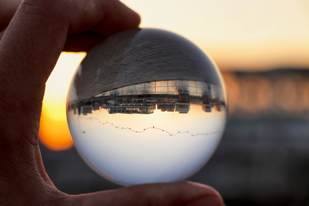 Crystal ball wih recletion of LimassolÂ´s harbour at sunset. Glass/Lens ball holding in hand with golden city lights and sea in the background reflecting the city of Limassol at sunset. Cyprusの写真素材