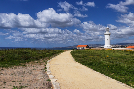 Scenery of Paphos city and nature. White lighthouse with old sand road. Pafos lighthouse for protection. Cypriot nature in spring. Sky with clouds. Traditional system for seaside cities.の写真素材