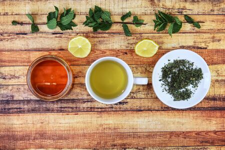 Foodstuffs for kept healthy. From left - brown honey, salvia hot tea, nettle on plate. Also lemons and mint leaves for immunity support. Concept of herbalism, and immunity.の写真素材