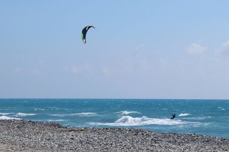 Practice in the sea. Training for race. Kiteboarder in Cyprus proficiently controls the parachute and enjoy race across coast. Wind day ideal for surfboard or this new sport kiteboarding.の写真素材