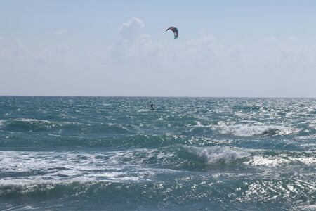 Kiteboarder is pulled across water by a power kite in Cyprus, Europe near famous Pissouri beach. Wonderful day with water activity. Active lifestyle. Special sport for connoisseur, gourmet.の写真素材