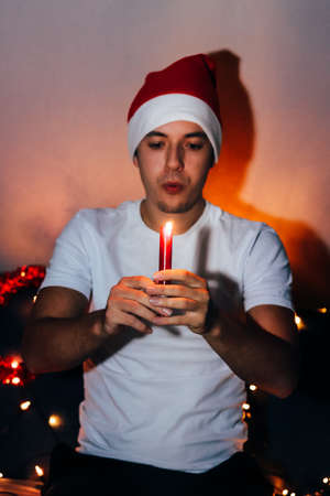 young man is about to blow out a candle at a Christmas party and wish something for the new year...