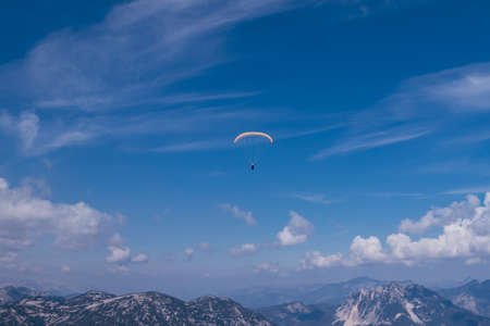 skydiver is playing with his life overDachstein Krippenstein at a height of 2.5 km. A man with a parachute circles over the Austrian Alps and Lake Hallstatter. Sunny weather and clear blue sky.の写真素材