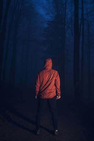 man stands motionless in a dark forest, trying to find himself thinking about his future. Feeling of emptiness, crampedness. The man is trying to fight his demons.の写真素材