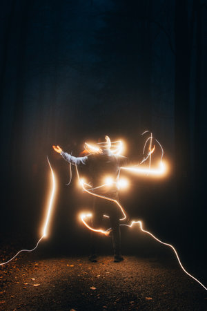 boy in the blue jacket is surrounded by yellow light in the dark. Visual effects at night. Long...