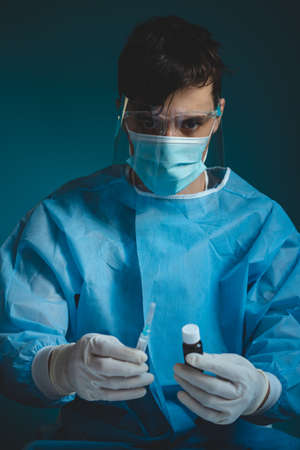 doctor in a protective shield, veil, and sterile gloved suit holds a single weapon against the...