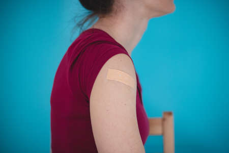 woman of European descent has a patch after being vaccinated after injecting the vaccine and now has to sit down.の写真素材