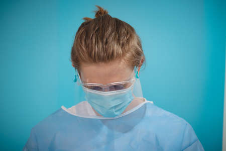 tired doctor after hard working hours in intensive care with  patients, still dressed in sterile clothes getting me sleeping against a headache. Destroyed paramedic after work in hospital.の写真素材