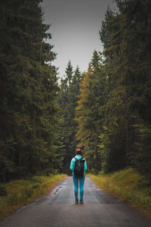 girl in sportswear and a tourist with a backpack stands motionless on a forest path between two different forests in the Jizera Mountains. Woman on a hike. A walk through the Czech wilderness.の写真素材