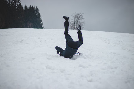 Athlete falls from a plastic snowboard and falls hard on the snow and sprawls. The boy's board got stuck and it threw him out and he did a somersault. Hard landing on the piste. Dangerous fall.の写真素材
