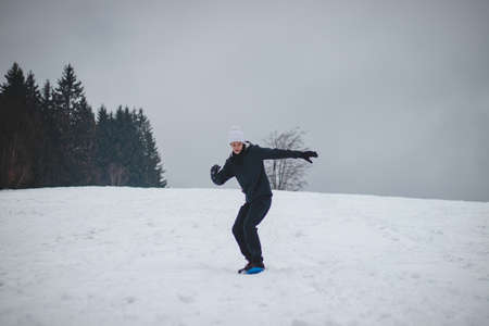sixteen year old boy rides a plastic blue snowboard. The teenager tries to keep his balance on the board. Ride an unstable board. They try new things. Winter sports. Skiing in the village. Smiling boy.の写真素材