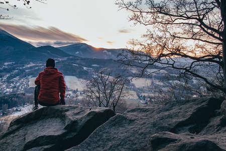 young boy in a red-brown jacket sitting on a bear rock in the Beskydy Mountains near Ostravice at...