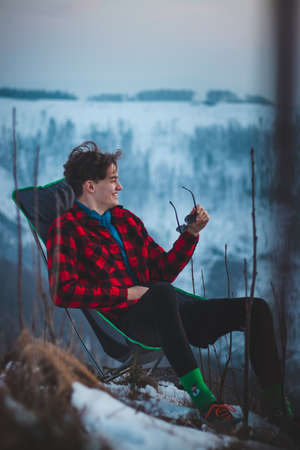 Candid portrait of a smiling teenager aged 15-20 of European descent sitting on a chair and dressed...