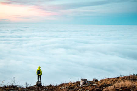 Amazing panorama of clouds floating all over the territory and a persistent boy of 20-25 years stands on a tree stump and enjoys this moment and tries to remember it. Enjoy hiking. Azure blue.の写真素材