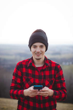 portrait of a twenty-three year old man in a black and red checked shirt, communicating with his...