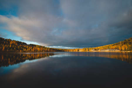 Autumn sunset at Lake Syvajarvi, in Hyrynsalmi, Finland. Reflection of red-orange petals on the lake surface. Storm clouds at sunset. Autumn vibes.の写真素材