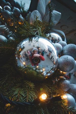 12/19/2021 - Vilnius. A young talented photographer takes a picture through a silver Christmas bank at the Christmas market in Vilnius, the capital of Lithuania.のeditorial素材