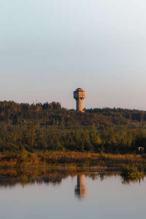 view of an abandoned mining tower by the infernal golden light near Kajaani, in the Kainuu region of central Finland. The tower is reflected on the lake. Biodiversity of Finland. Coniferous forests.の写真素材