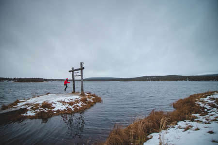 Woman in a red jacket enjoys a wooden swing in the town of Ã„kÃ¤slompolo in Lapland, Finland on...