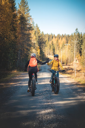 Cycling friends greet each other as they meet on a dirt road in Vuokatti area, Kainuu, Finland. Female cyclists in sportswear on fat bikes.の写真素材