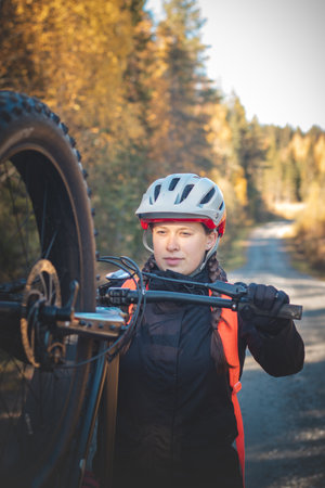 Young likeable lady with a lovely realistic smile while recreationally sporting. Cyclist riding fat bike in Finnish wild nature. Vuokatti area. Cycling clothing and helmet.の写真素材