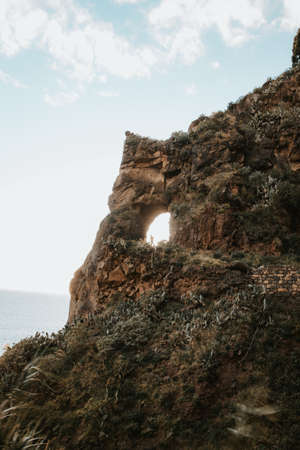 Rock opening near the town of Ponta do Sol on the island of Madeira, Portugal at sunset. The sun...