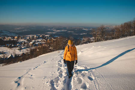 Traveler with a pleasant smile in a distinctive yellow jacket stands on top of a hill in the Polish...