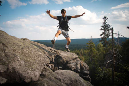 Swarthier type of man is running down a gravel hill, checking his every step to avoid injury. Active...