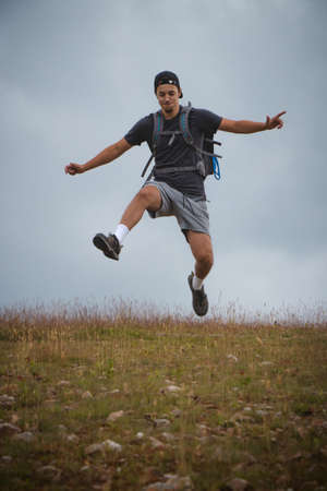 Swarthier type of man is running down a gravel hill, checking his every step to avoid injury. Active athlete runs over challenging terrain to improve fitness, coordination and precision of movement.の写真素材