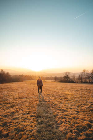Young ambitious tourist walks through the grain fields at sunset in the Beskydy Mountains, Czech Republic. Reflecting on himself. A walk in the fresh air.の写真素材