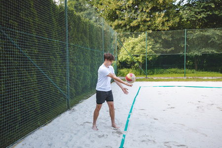 Volleyball player practicing a bump pass on a sand court, focusing on technique and control. Captured in an outdoor setting, showcasing beach volleyball skills and training.の写真素材