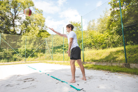 Volleyball player practicing a bump pass on a sand court, focusing on technique and control. Captured in an outdoor setting, showcasing beach volleyball skills and training.の写真素材